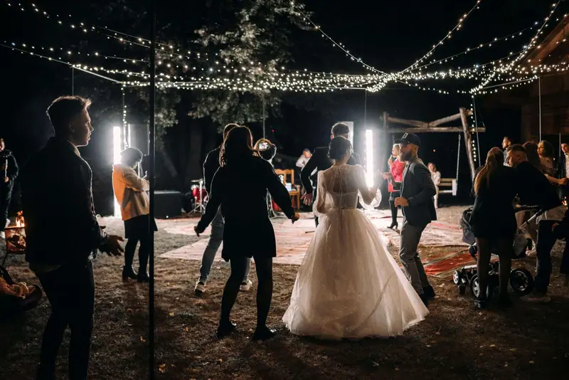 Still from a wedding highlight film: the couple dancing under string lights